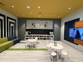 A modern room with a sofa, chairs, a table, and a television.
