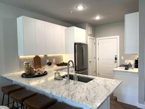 A kitchen with a marble countertop and white cabinets.