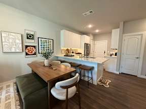 A kitchen with a table and chairs in the foreground and a fridge in the background.