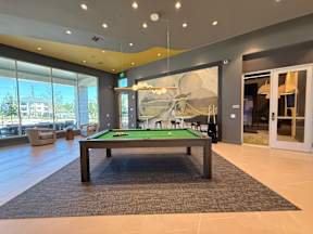 A billiard table in a room with a large painting on the wall.