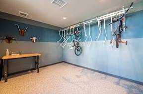 A room with a blue wall and a white ceiling with a table and bikes hanging on the wall.