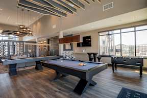 A pool table in a room with a bar and a tv.