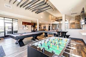 A foosball table is in the middle of a room with a pool table and a bar.