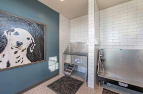 A dog painting hangs on a wall next to a stainless steel sink.