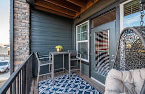 A small table with a vase of flowers on it sits on a porch.