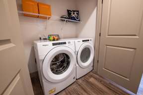 A pair of white front loading washing machines in a laundry room.