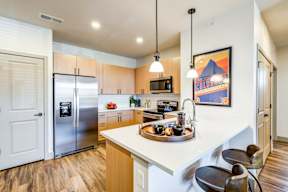A kitchen with a refrigerator, microwave, and oven.