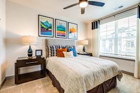 A bedroom with a bed, nightstand, and pictures on the wall.