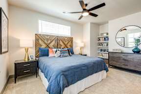 A bedroom with a bed, nightstands, and a ceiling fan.