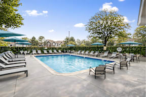 A large outdoor swimming pool surrounded by lounge chairs and umbrellas.