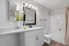 A bathroom with a marble countertop and a large mirror above it.