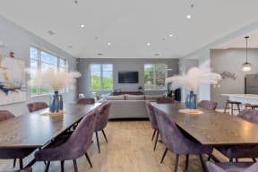 two large wooden dining tables behind a seating area with a mounted TV