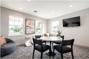 A modern living room with a grey sofa, a white table, and a flat screen TV mounted on the wall.
