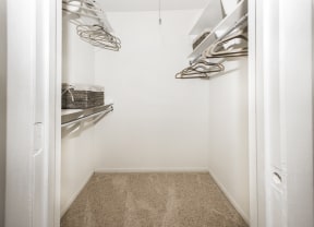 a walk in closet with white walls and shelves and a carpet