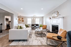 A modern living room with a white sofa, a coffee table, and a fireplace.