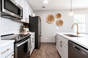 A black fridge in a white kitchen.