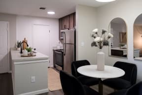 a dining area with a small white table and four black chairs