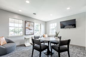 Littlestone Apartments community lounge with a table in front of a mounted tv