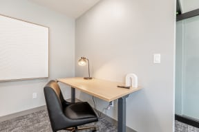 desk with a table lamp and black chair in Littlestone Apartments community lounge