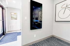 A modern art piece is hanging on the wall in a brightly lit room.