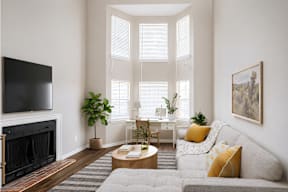 A living room with a grey couch, a fireplace, and a painting on the wall.