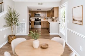 A dining room with a table and chairs and a tree in a pot.