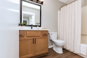 A bathroom with a toilet, sink, and mirror.