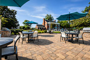 A patio with tables and chairs under umbrellas.