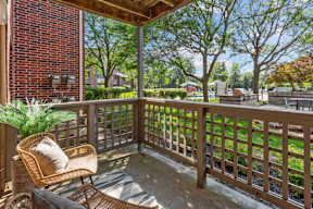 A wooden chair with a cushion is on a wooden deck.