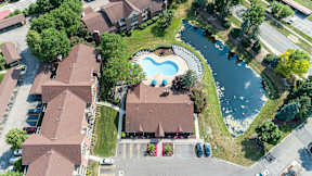 A bird's eye view of a residential area with houses, a swimming pool, and a river.