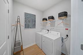 A laundry room with a washer and dryer and a clothes rack.