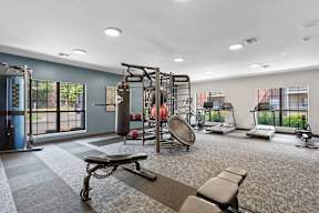 A gym with a variety of equipment including a bench, weights, and a treadmill.