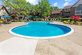 A round blue swimming pool surrounded by a concrete patio and a white border.