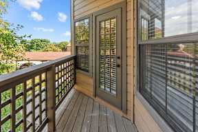 A wooden deck with a glass door and window.