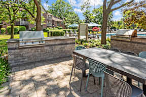 A patio with a table and chairs and a grill.