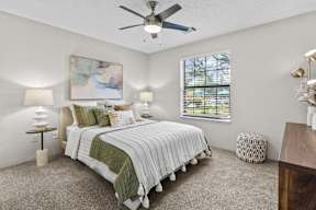 A bedroom with a large bed and a ceiling fan.