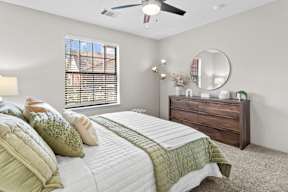 A bedroom with a large bed, a dresser, and a ceiling fan.