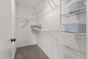 A white walk-in closet with shelves and a door.