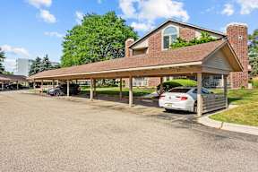 A car is parked in a parking lot under a covered structure.