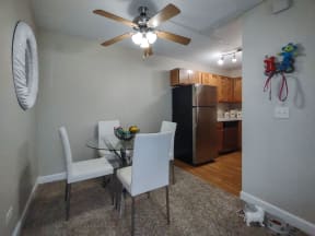 a dining room with a table and chairs and a kitchen with a refrigerator