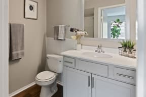 a bathroom with white cabinets and a white toilet next to a white sink with a mirror above