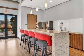 a kitchen with a long island with a row of red bar stools in front of it