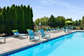 a swimming pool with blue lounge chairs and green umbrellas