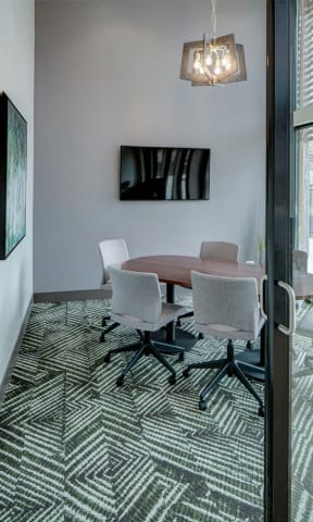a conference room with a table and chairs and a television