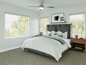 A bedroom with a large bed and a ceiling fan.
