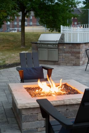 patio with a fire pit, Adirondack chairs, and a grilling station at Valley Creek Apartments