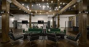 A modern office space with a green couch and black chairs.
