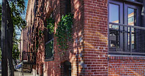 A red brick building with a balcony and a door.