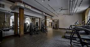 A gym with a variety of equipment including treadmills, weights, and exercise machines.