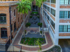 A courtyard surrounded by brick buildings with a fence and a tree.